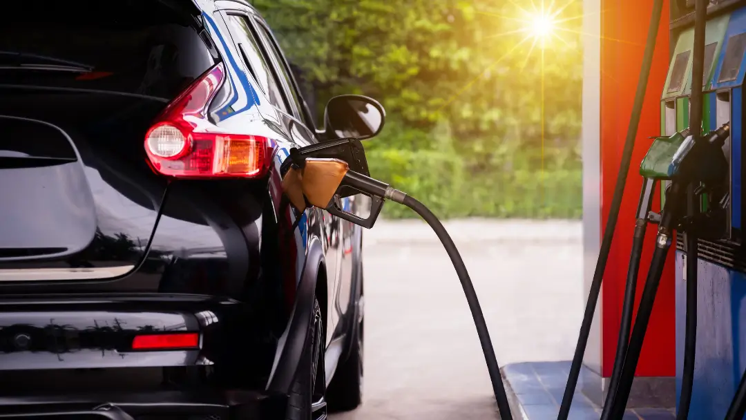 A car with tinted windows getting fuel from a fuel pump