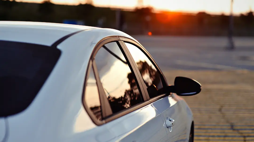 A picture of a white car with tints, in the background the sun is setting